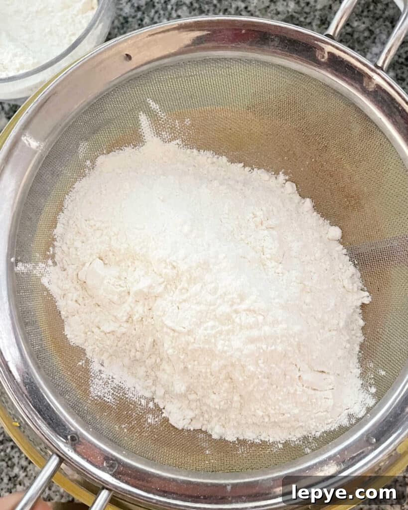 Sifting flour mixture over a bowl.
