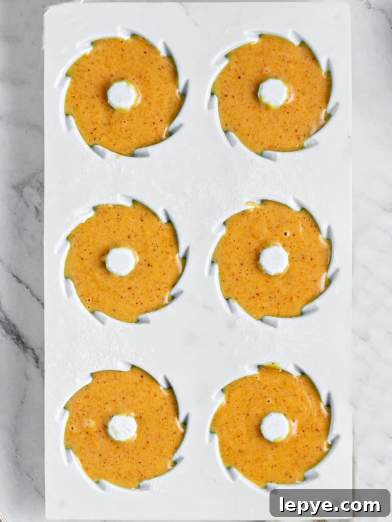 Gray silicon mold with pumpkin mini bundt cake batter. Top view.