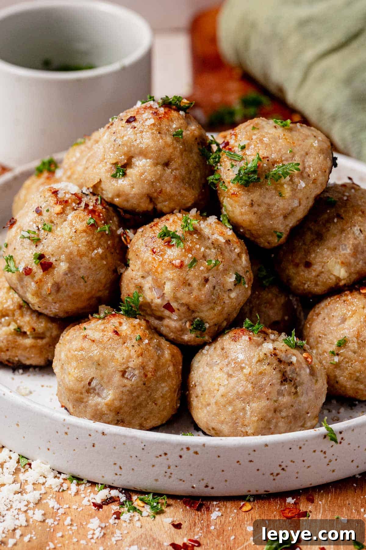 Oven-Baked Turkey Meatballs with Savory Herb Sauce 3 A plate of baked turkey meatballs topped with parmesan and parsley.