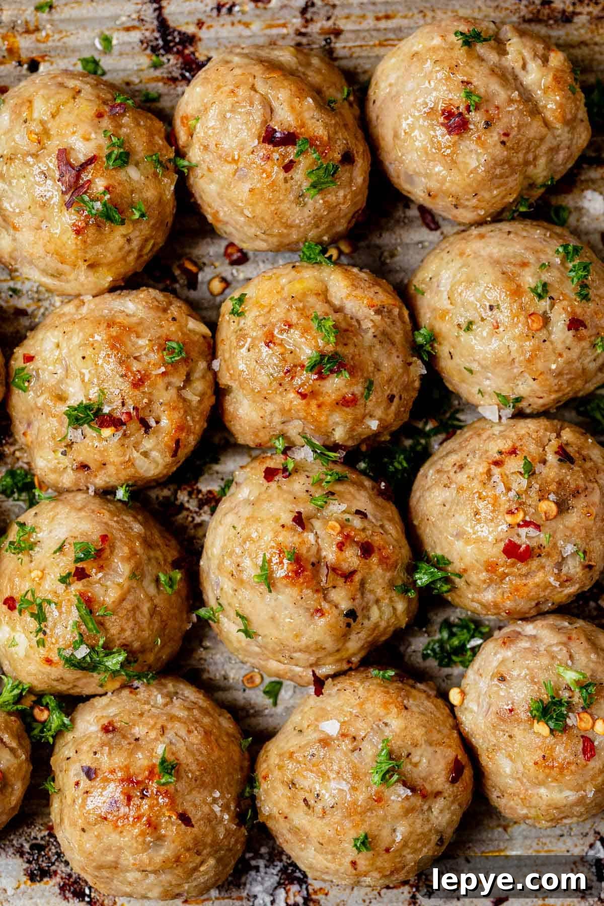 Oven-Baked Turkey Meatballs with Savory Herb Sauce 8 baked turkey meatballs cooling on a sheet pan.