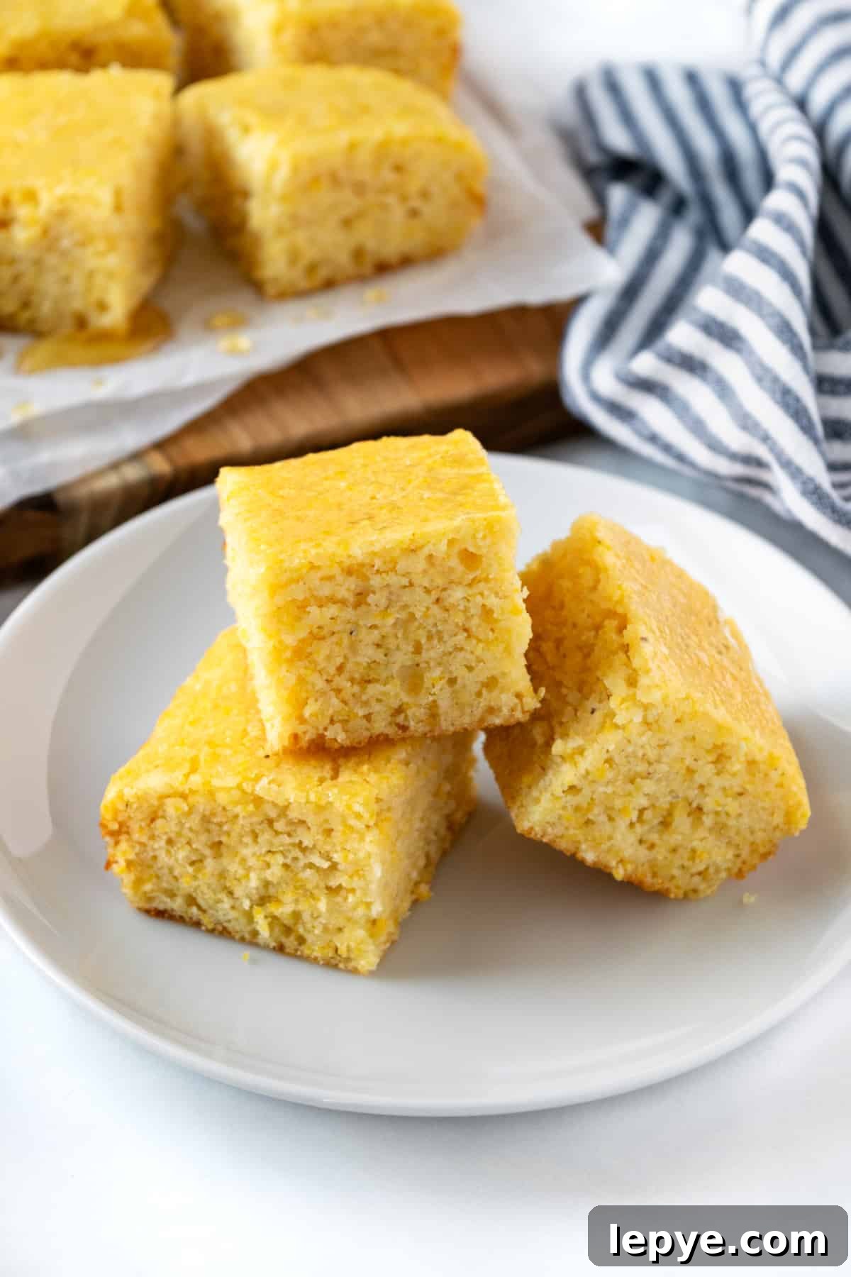 Honey-Glazed Cornbread Recipe with Golden Crust and Sweet Drizzle 2 Three pieces of cornbread stacked on a white plate.