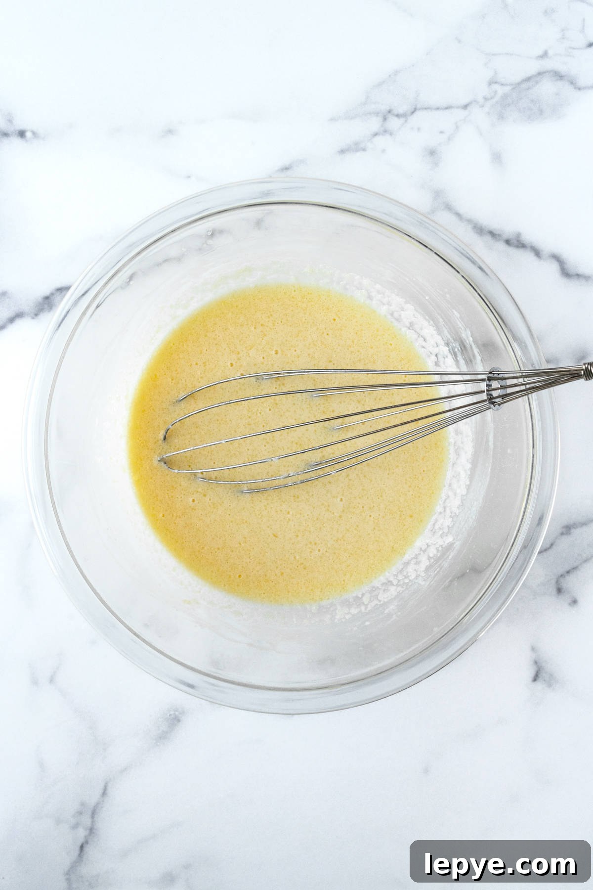 Honey-Glazed Cornbread Recipe with Golden Crust and Sweet Drizzle 5 Cornbread wet ingredients in a glass bowl with a whisk.