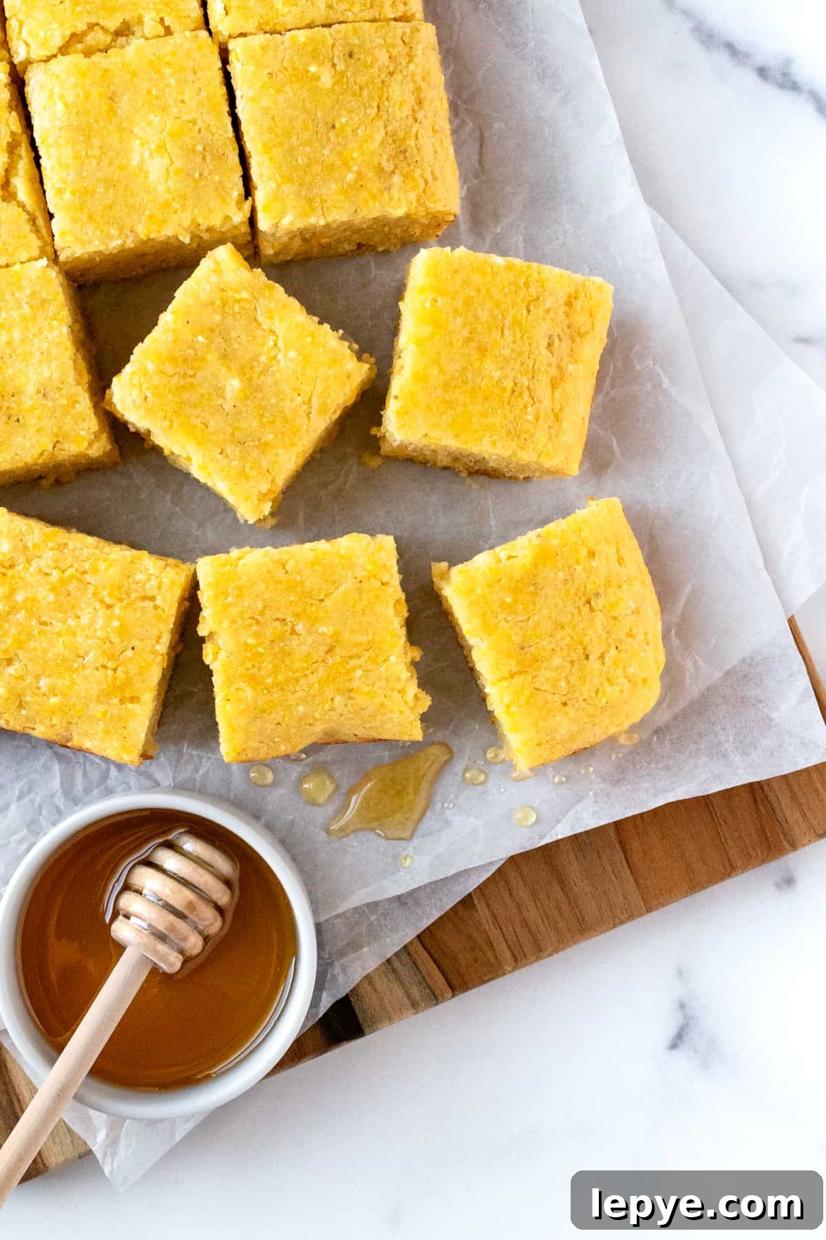 Honey-Glazed Cornbread Recipe with Golden Crust and Sweet Drizzle 6 Honey Glazed Cornbread cut into squares on a parchment lined serving board.