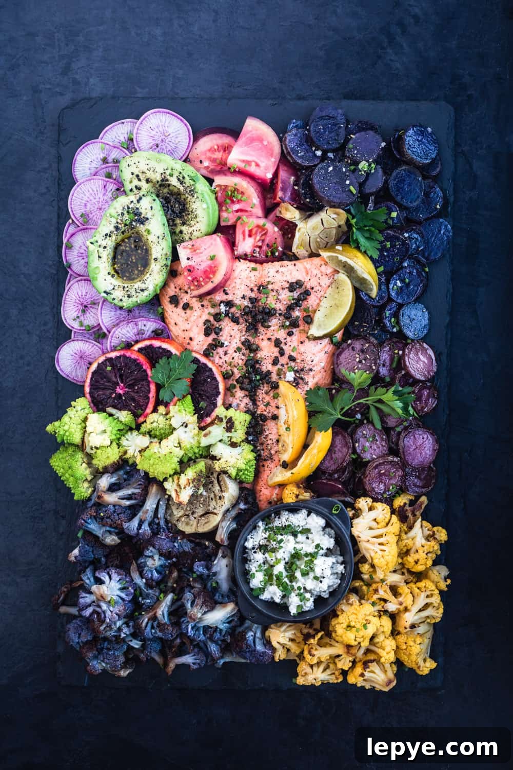 Vibrant Salmon Rainbow Salad Board for Entertaining 5 Salmon Rainbow Party Salad Board with ninja radishes, avocado, tomatoes, purple and pink potatoes, garlic, yellow and purple cauliflower, romanesco, blood oranges, garlic, lemons, limes and cheese sprinkled with fresh herbs and fried capers.