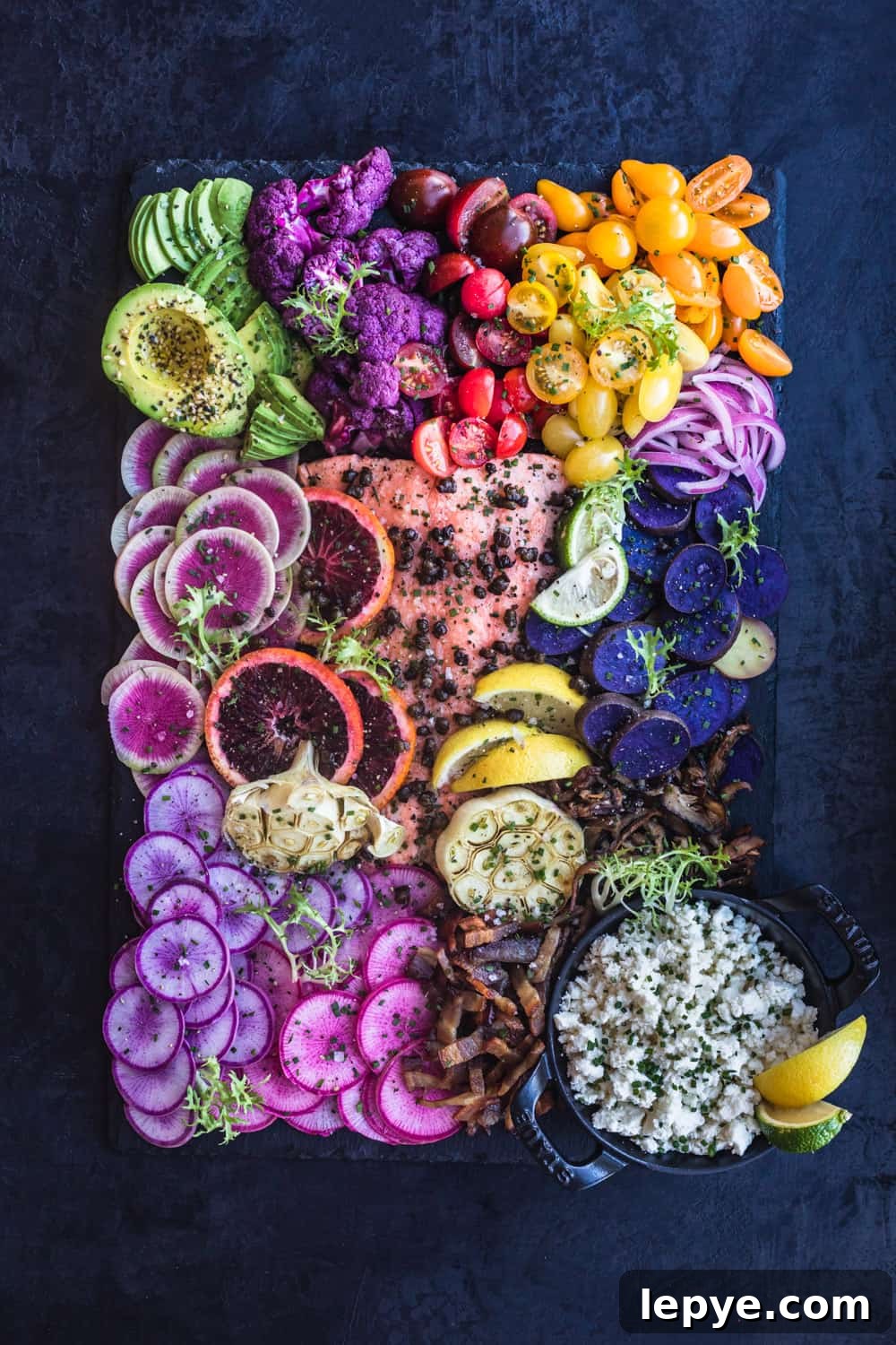 Vibrant Salmon Rainbow Salad Board for Entertaining 6 Salmon Rainbow Party Salad Board with avocado, purple cauliflower, tomatoes, red onions, purple patties, pink and purple radishes, bacon, cheese, garlic, blood orange, lemons, limes and watermelon radishes. Up close. Overhead shot,