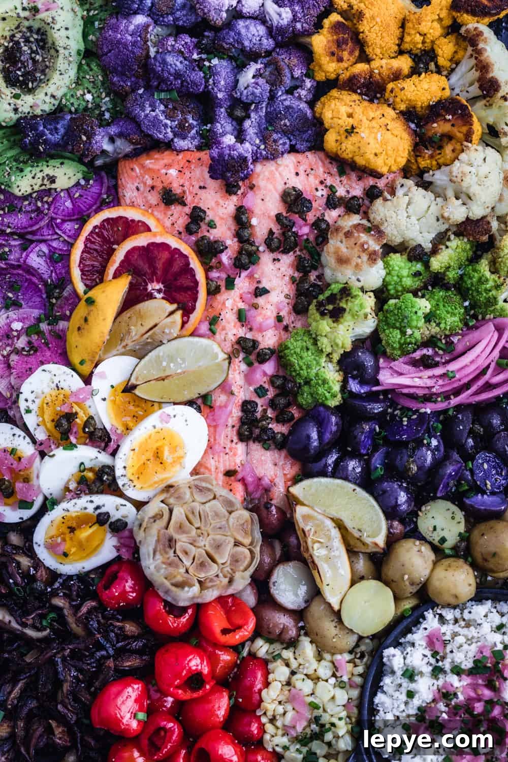 Vibrant Salmon Rainbow Salad Board for Entertaining 7 Salmon Rainbow Party Salad Board with avocado, purple, white, green and yellow cauliflower, pickled red onions, purple and white potatoes, corn, cheese, peppers, garlic, mushrooms, soft boiled eggs, ninja and watermelon radishes, blog oranges, lemons, limes, fried capers and shallots. Up close shot.