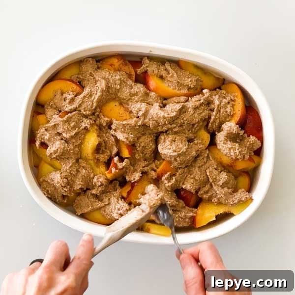 Gluten-Free Peach Cobbler with Almond Butter Caramel Sauce 15 Spooning the peach batter over the peaches in a shallow dish.