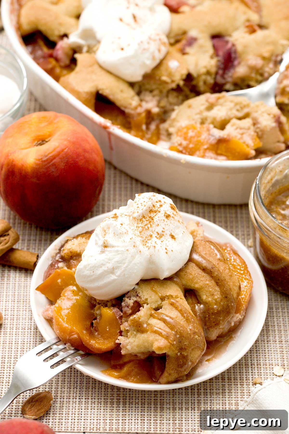 Gluten-Free Peach Cobbler with Almond Butter Caramel Sauce 16 Gluten-free peach cobbler with oat and almond flour and whipped cream on top.