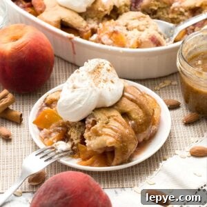 Gluten-Free Peach Cobbler with Almond Butter Caramel Sauce 17 A plate of gluten-free peach cobbler with oat and almond flour and whipped cream on top.
