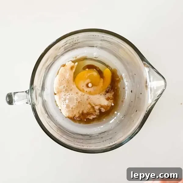 Gluten-Free Peach Cobbler with Almond Butter Caramel Sauce 10 Adding the wet ingredients for the peach cobbler batter to a glass mixing bowl.