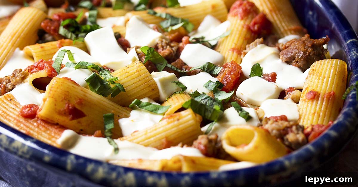 Close up of rigatoni and melted mozzarella in a casserole dish of baked pasta with sausage.