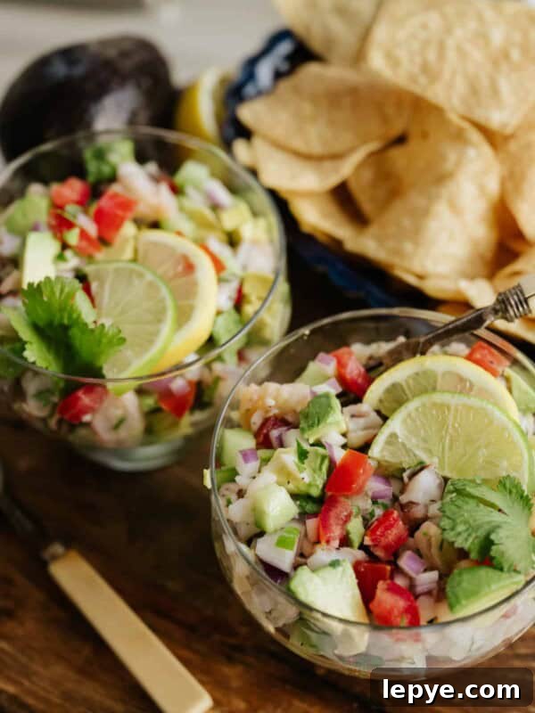 Mexican Shrimp Cocktail Recipe: Zesty Camarones en Coctel 9 two glass goblets filled with mexican shrimp ceviche de camaron and topped with lemon and lime wedges.