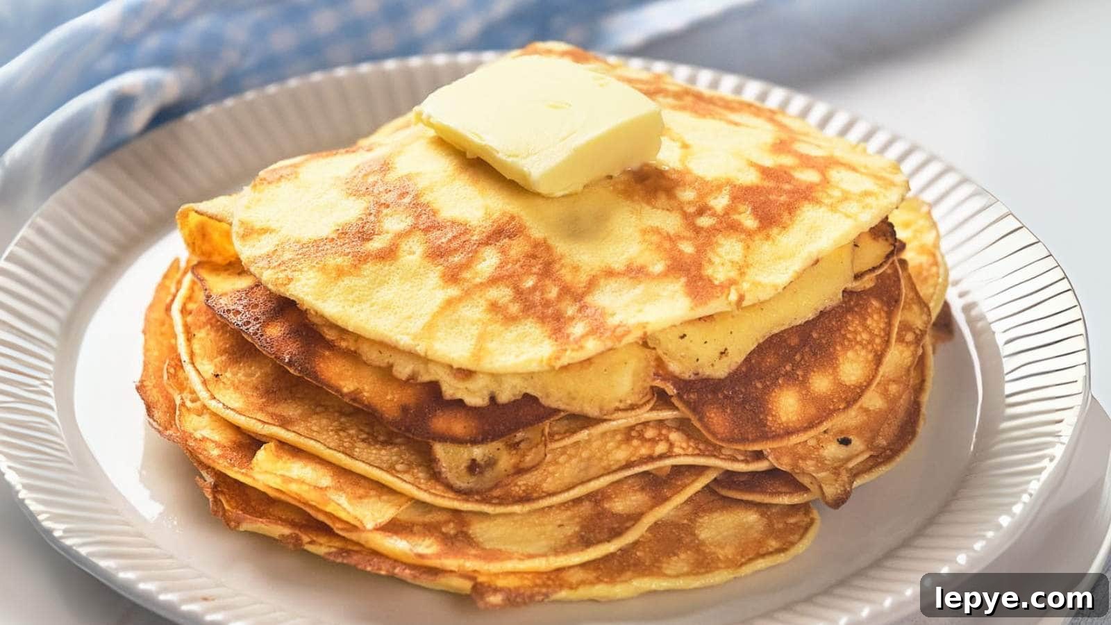 15 High-Protein Breakfasts to Power Your Morning Hustle 3 A stack of golden pancakes topped with a square of butter on a white plate.