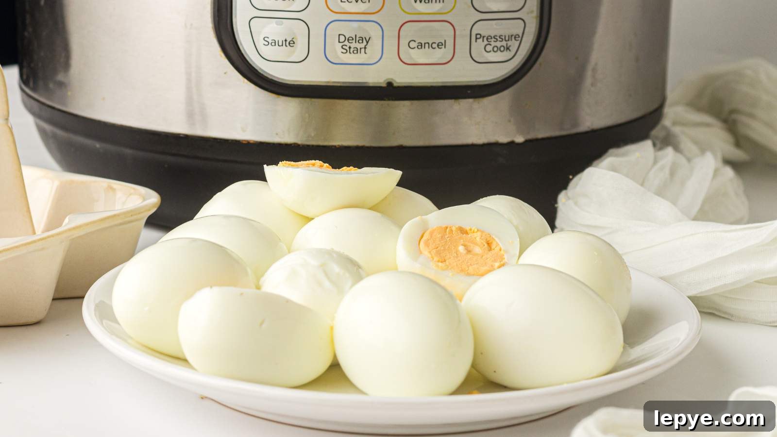 15 High-Protein Breakfasts to Power Your Morning Hustle 5 A plate of peeled hard-boiled eggs is placed in front of an instant pot on a white countertop.
