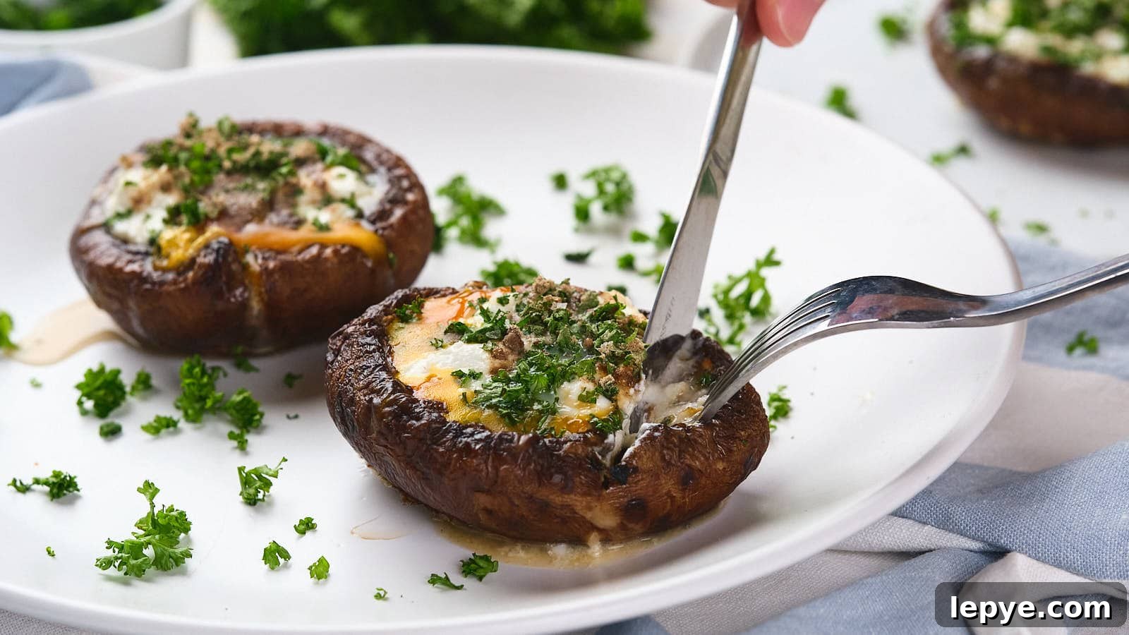 15 High-Protein Breakfasts to Power Your Morning Hustle 8 A fork and knife cutting into an egg in mushroom with green garnish visible in the background.