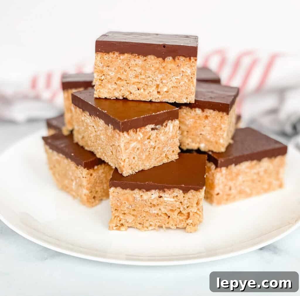 A plate stacked with peanut butter and chocolate Rice Krispies Treats. A red striped towel in the background.