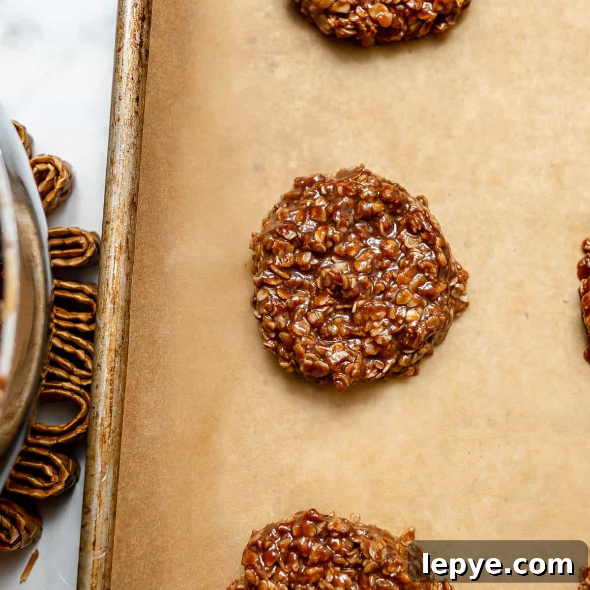 A close-up of no-bake chocolate oatmeal cookies on a parchment-lined baking sheet.