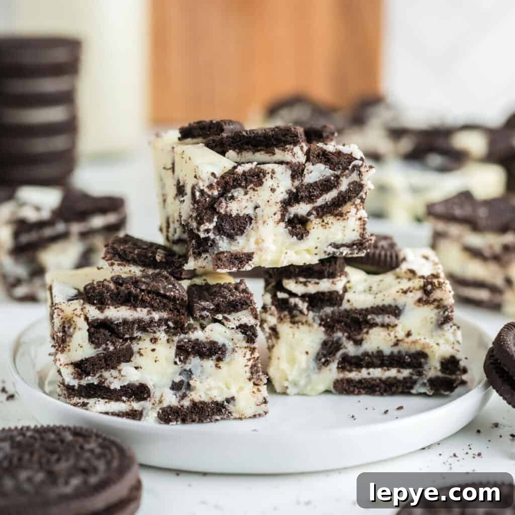 A stack of cookies and cream fudge squares on a white plate, surrounded by whole sandwich cookies.