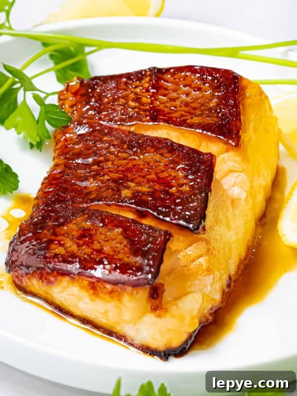 Asian sea bass pan seared with crispy skin side up on a white plate next to herbs.