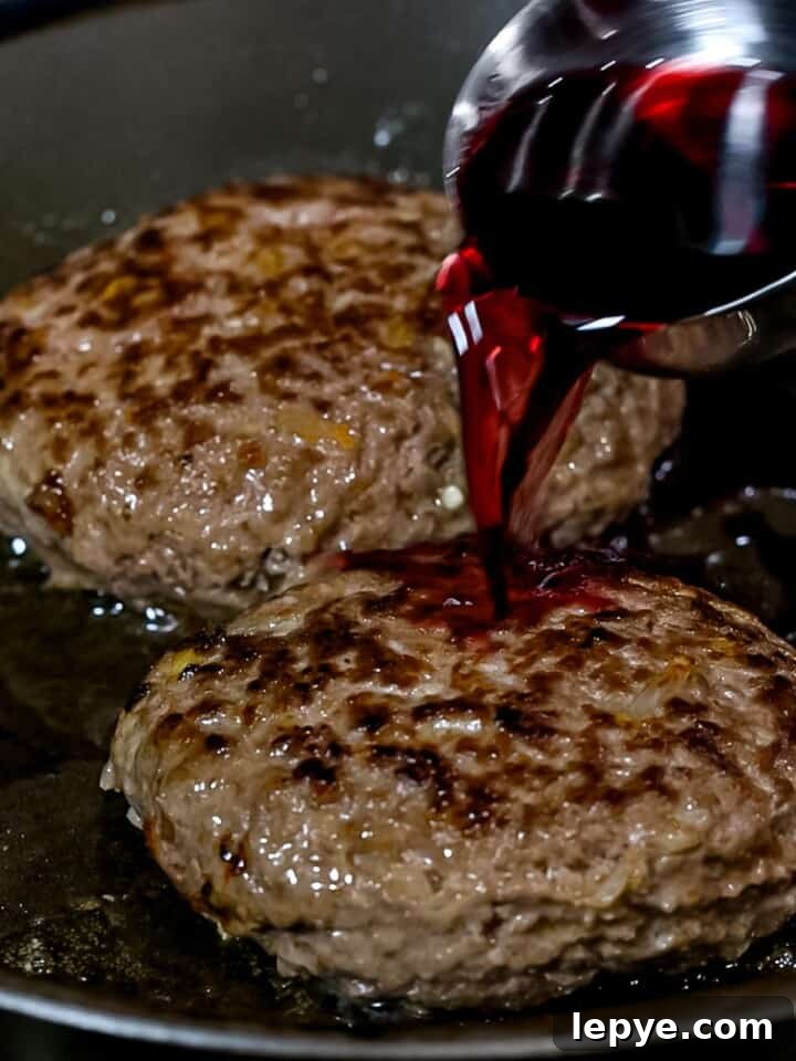 Red wine being added to Japanese hamburger steaks cooking in a pan.
