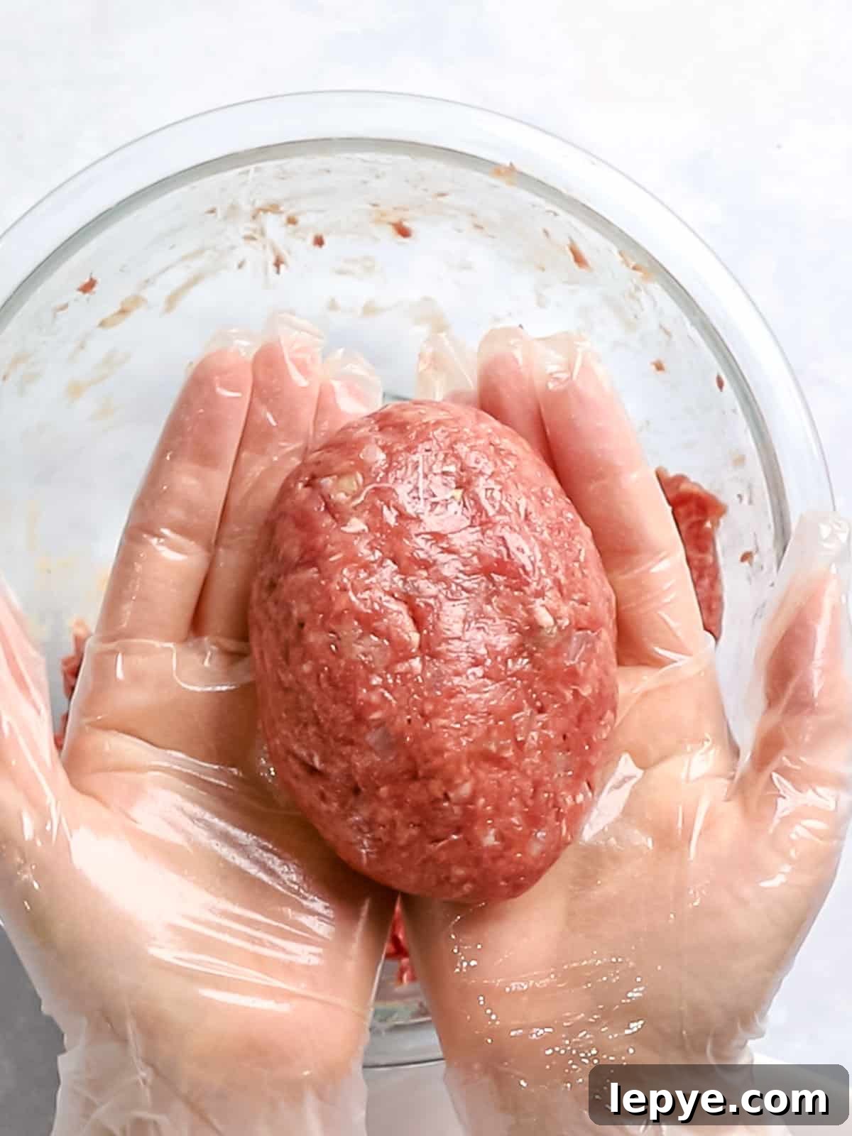 Hambagu patty of ground meat formed into a round oval shape and held in hands.