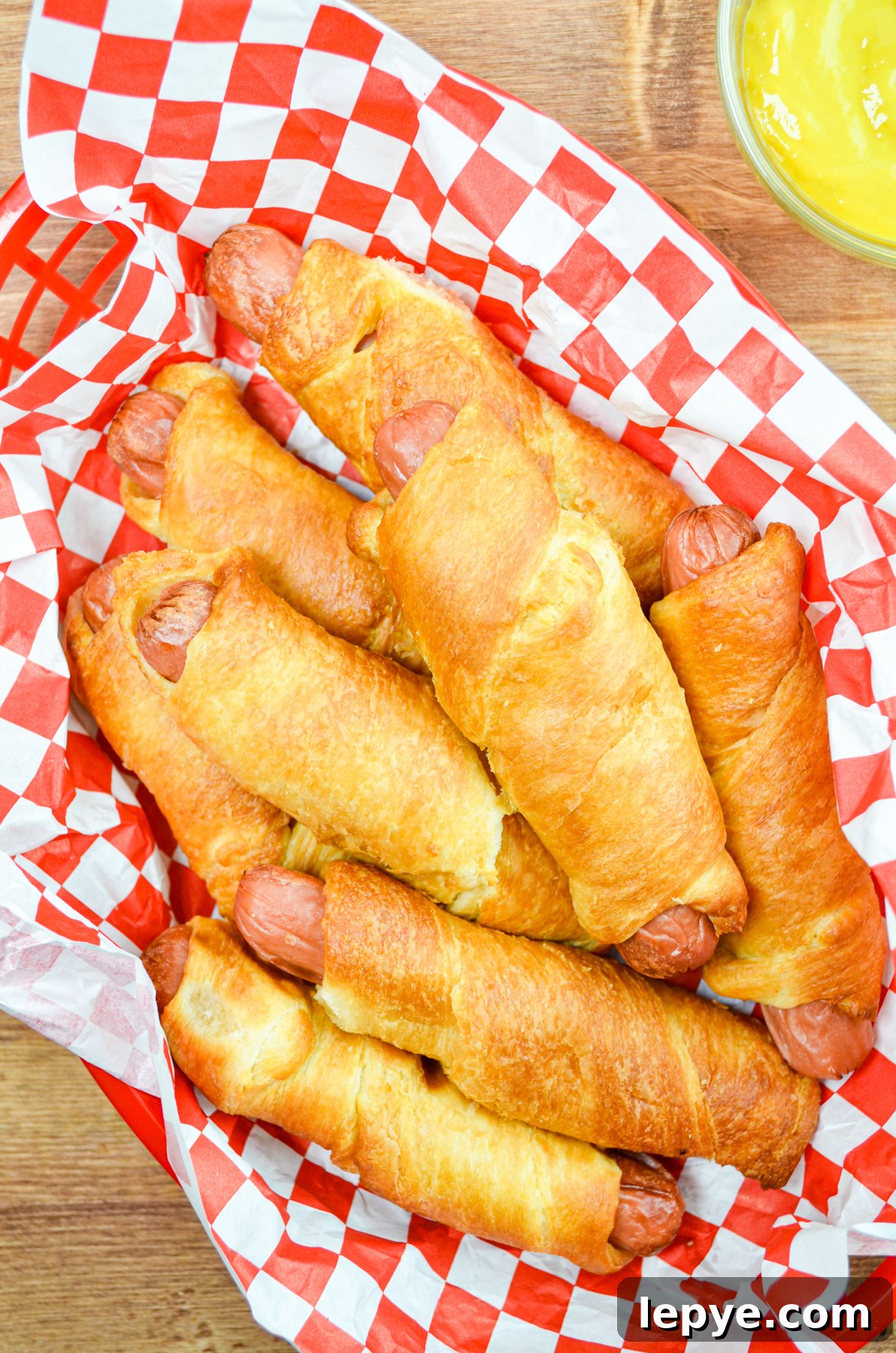 Crispy Air Fryer Pigs in a Blanket Recipe 9 A basket full of pigs in a blanket, with mustard on the side.