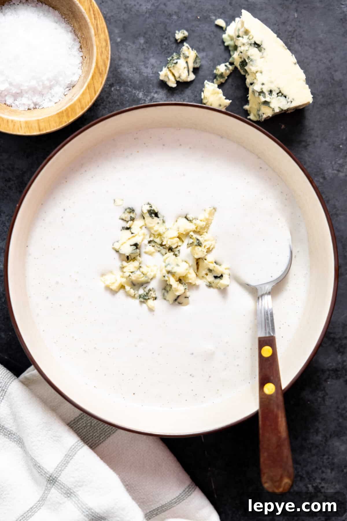 Creamy Blue Cheese Dressing Recipe for Salads and Wings 2 Blue cheese dressing in a bowl topped with crumbled cheese.