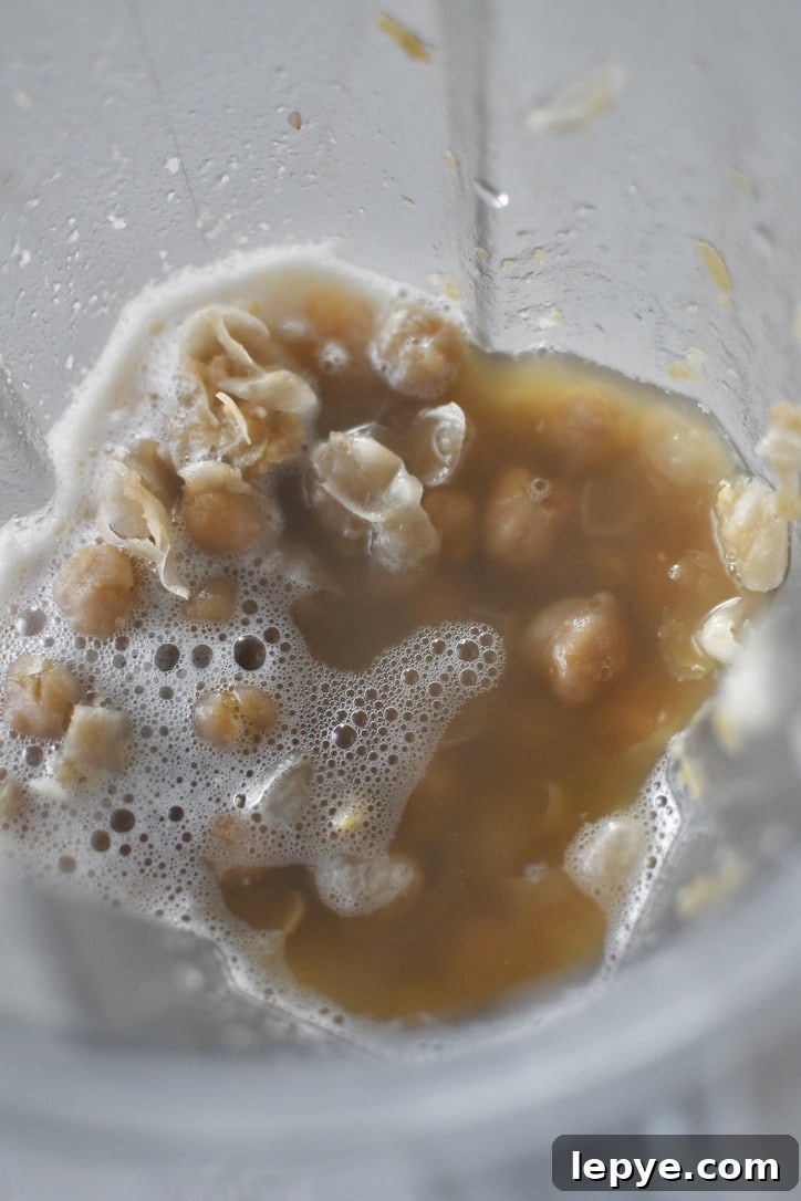 Cooked chickpeas in a high speed blender with the cooking liquid ready to be pureed.