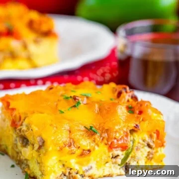A plated slice of breakfast casserole loaded with sausage, peppers, and melted cheese