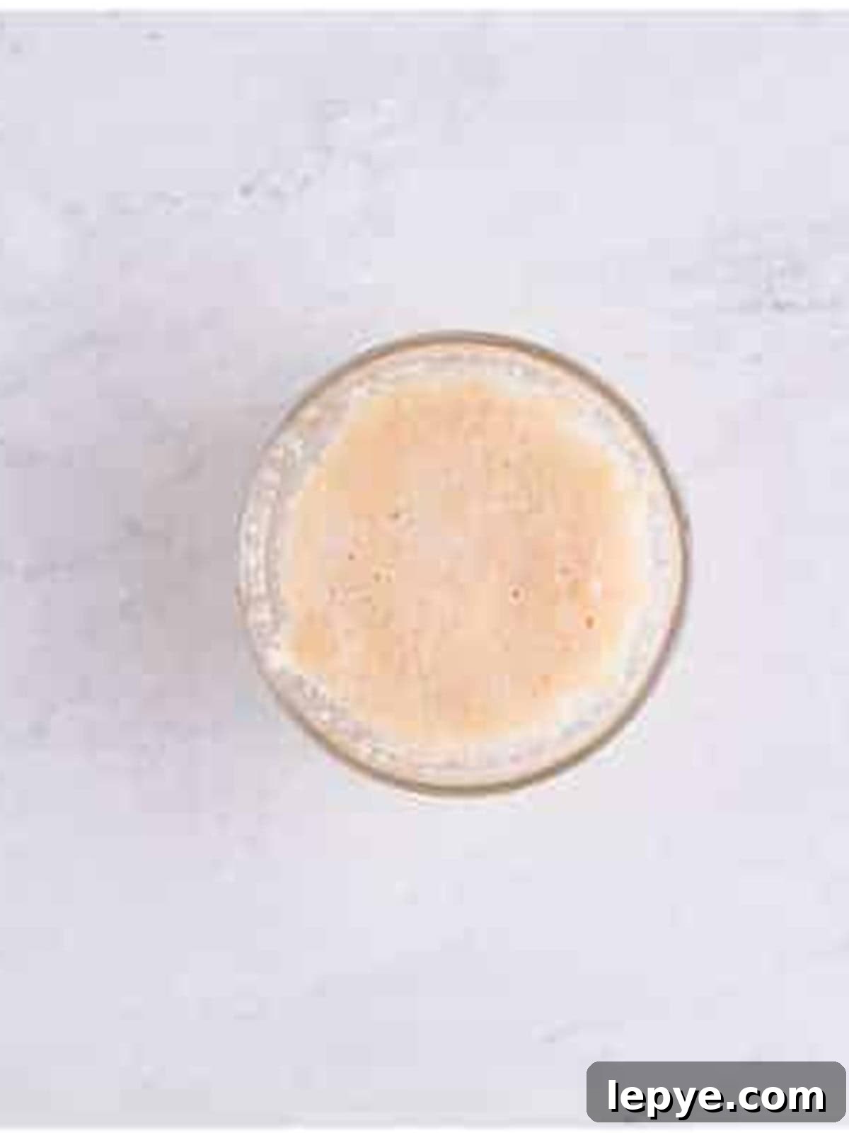 Active dry yeast blooming in warm water and sugar in a glass bowl.