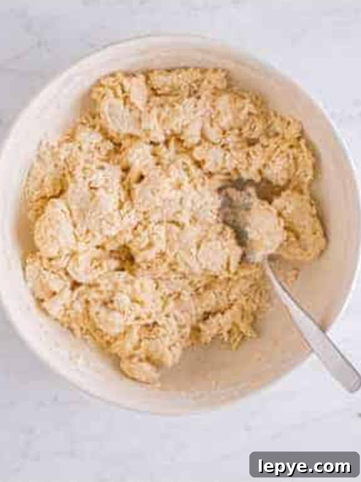Shaggy English muffin dough coming together in a bowl.