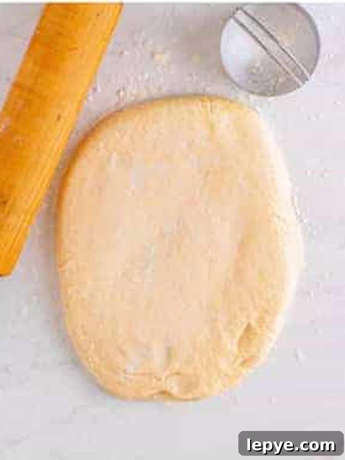 English muffin dough rolled out on a floured surface.
